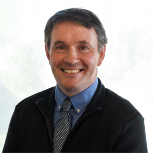 Smiling man in a blue shirt with a patterned tie and a black jacket (portrait)